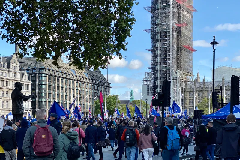 Crowd with EU flags marching near scaffolded Big Ben at a protest in Parliament Square, London