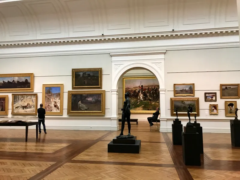 Grand gallery with gold-framed oil paintings, bronze sculptures, and parquet floors in a classical art museum