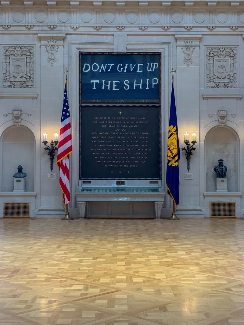 Perry's "Don't Give Up the Ship" flag and memorial plaque flanked by flags in Memorial Hall at the Naval Academy