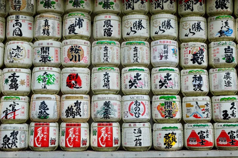 Rows of decorative sake barrels with colorful Japanese calligraphy stacked at a Shinto shrine