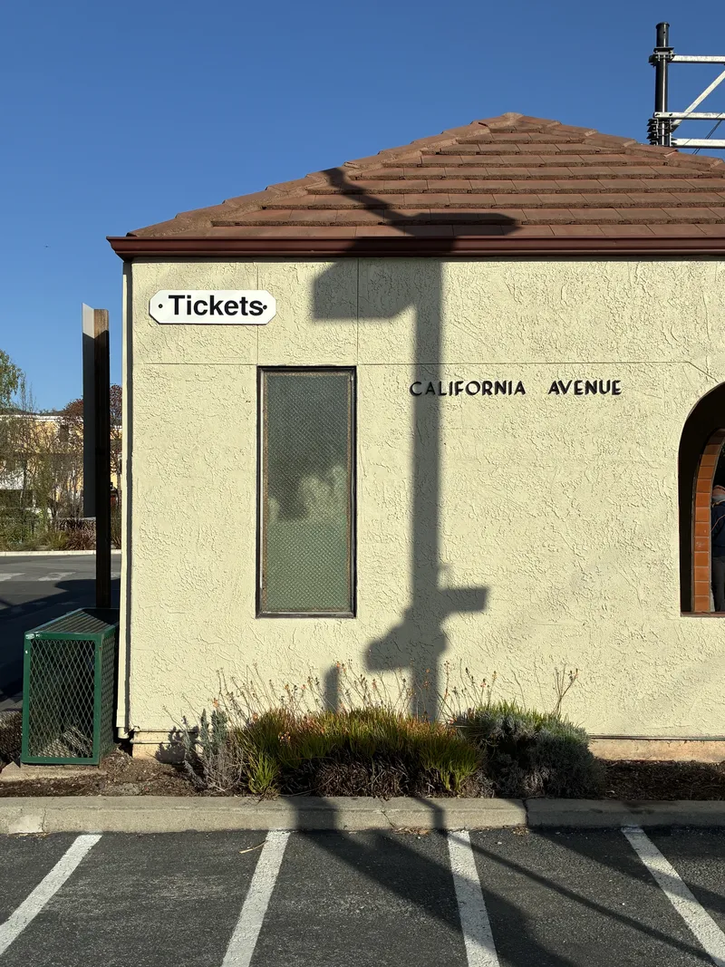 Small beige California Avenue Caltrain station ticket building on a clear day