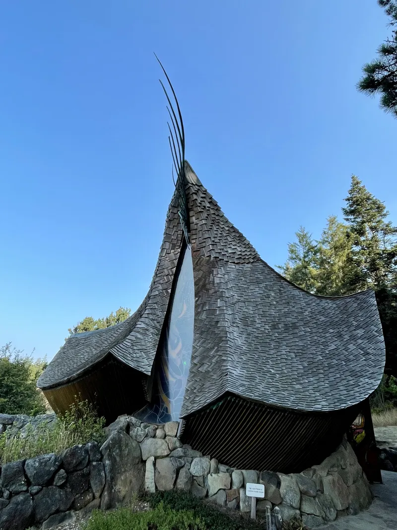 Swooping shingled roofline of an organic architecture building rising like wings against a clear sky