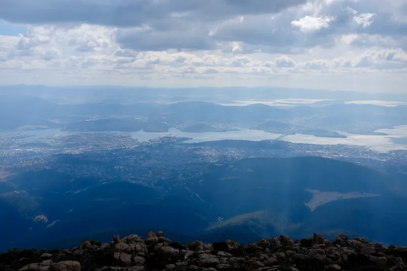 Hobart and the Derwent River seen from the rocky summit of Mount Wellington under hazy clouds