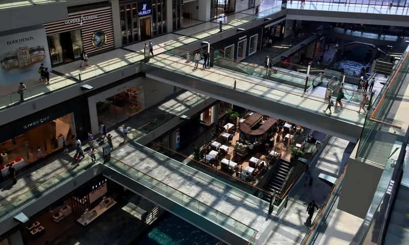 Multi-level luxury shopping mall interior with glass walkways, a canal, and shoppers at Marina Bay Sands