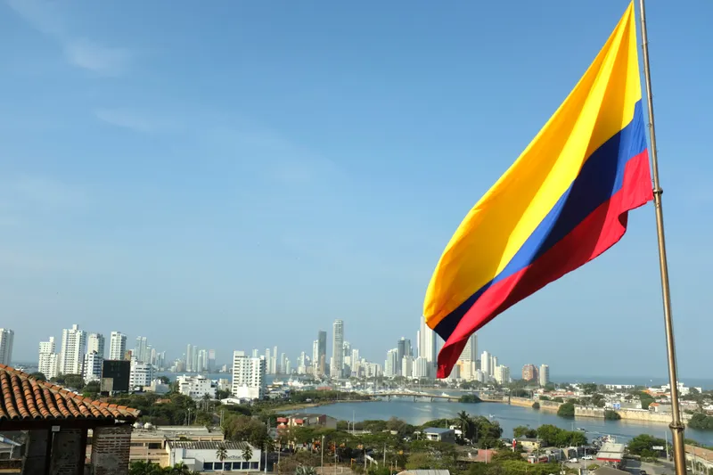 Colombian flag waving above Cartagena with the modern skyline and harbor in the background