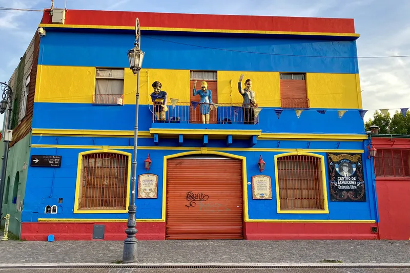 Brightly painted blue and yellow building with figures on the balcony in La Boca, Buenos Aires