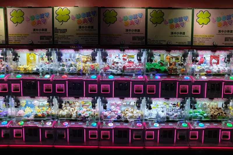Rows of pink neon-lit claw crane machines filled with stuffed animals in a Taiwanese arcade